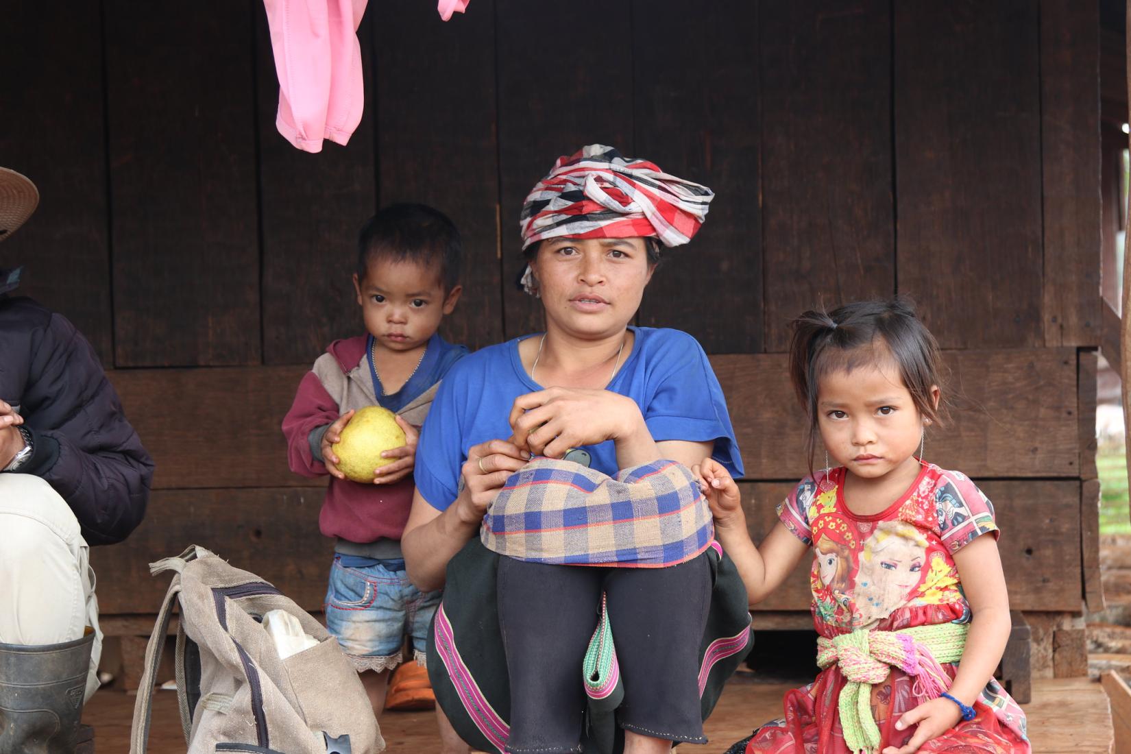 A rural Lao family in the countryside sits together in front of their home.