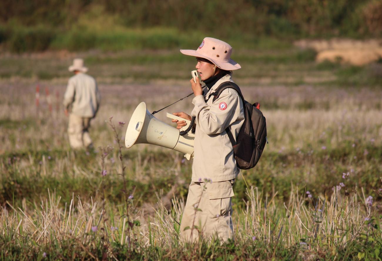 A UXO Lao expert Phonenida Mixaivanh uses a speaker to warn the community that the mine clearance begins.