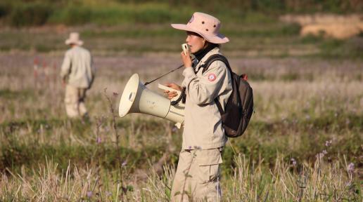 A UXO Lao expert Phonenida Mixaivanh uses a speaker to warn the community that the mine clearance begins.